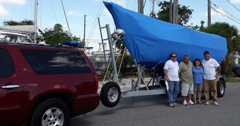 Boat Covered on a Trailer with a Group of People 